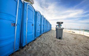 line of porta potties on the beach with a hand washing station